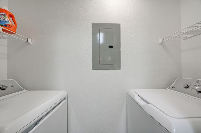 Modern laundry room with sleek washer and dryer, featuring ample storage shelving and efficient design.