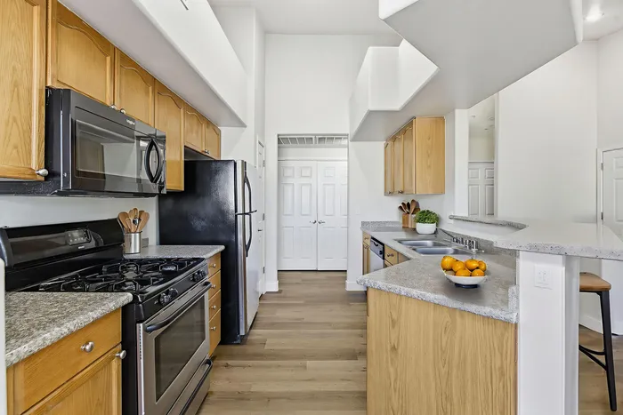 Modern kitchen with sleek black appliances, spacious countertops, and warm wooden cabinetry, perfect for culinary creativity.