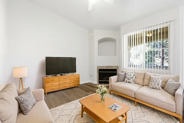 Bright and inviting living room with large windows, cozy sofas, elegant decor, and a modern fireplace.