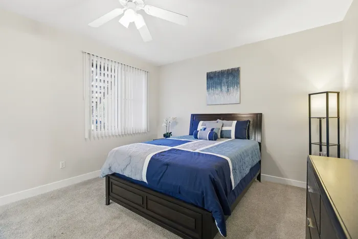 Bright and inviting bedroom with modern design, featuring a plush blue bed, elegant decor, and a serene atmosphere.