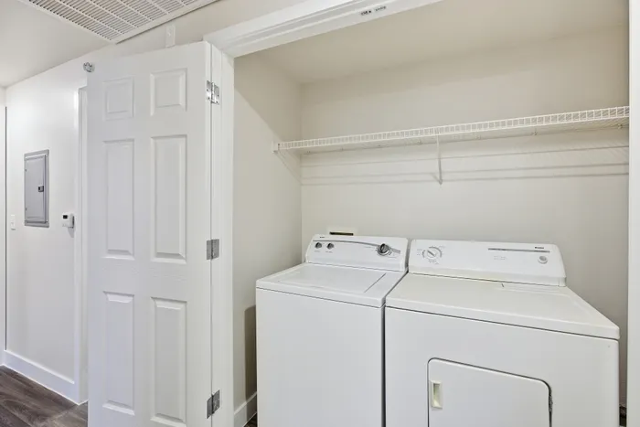 Modern apartment laundry room equipped with washing machine and dryer, complemented by sleek shelving and a bright, inviting atmosphere.
