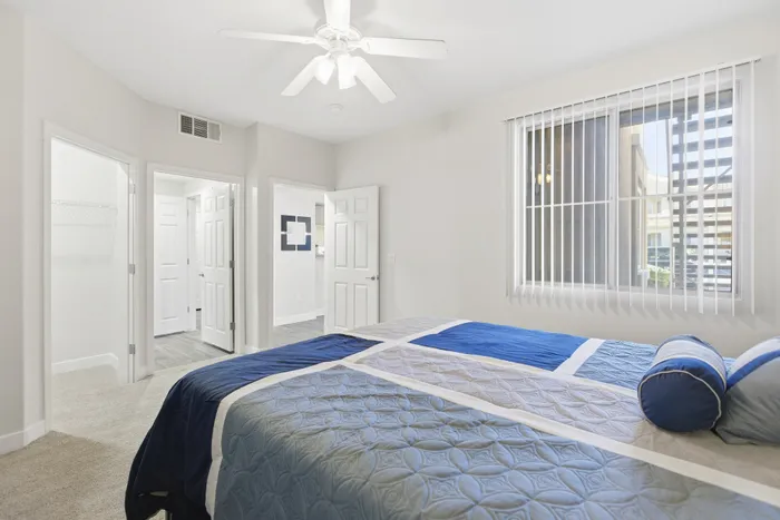 Bright and airy bedroom featuring modern decor, plush bedding, and large window with vertical blinds.