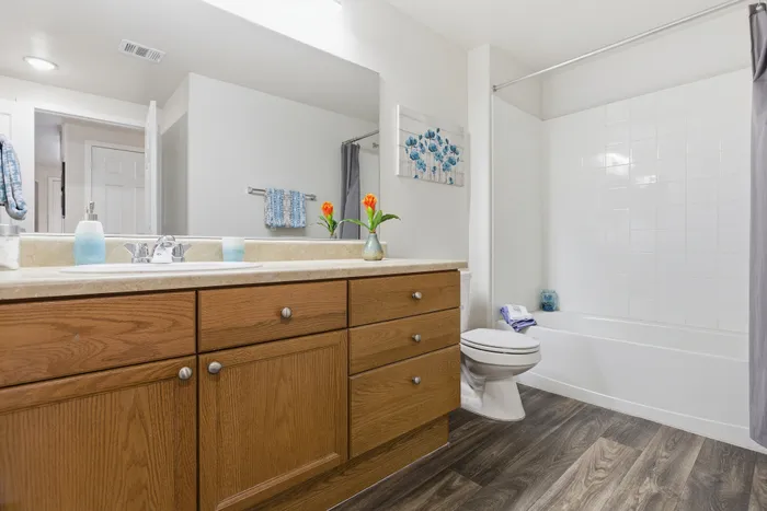 Elegant bathroom showcasing a sleek white tub, stylish wooden vanity with fresh decor, and modern finishes.