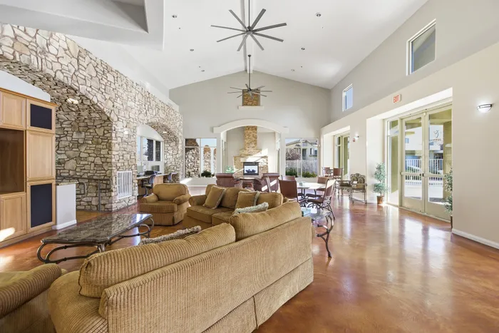 Elegant apartment lounge with high ceilings, stylish stone walls, and plush seating area.