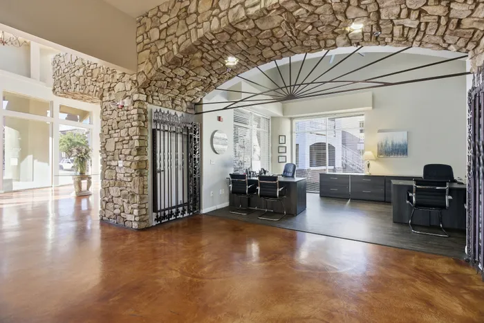 Luxurious office space with rustic stone archway, modern furnishings, and bright natural light flooding through large windows.