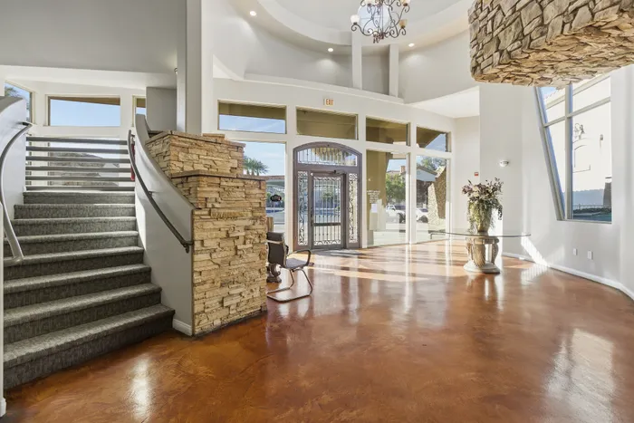 Elegant apartment entrance with grand staircase, rustic stone accents, and large sunlit windows.