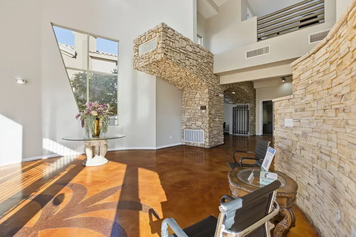 Elegant interior showcasing a stunning stone accent wall, large modern window, and vibrant polished floor with decorative design, perfect for a stylish and inviting living space.