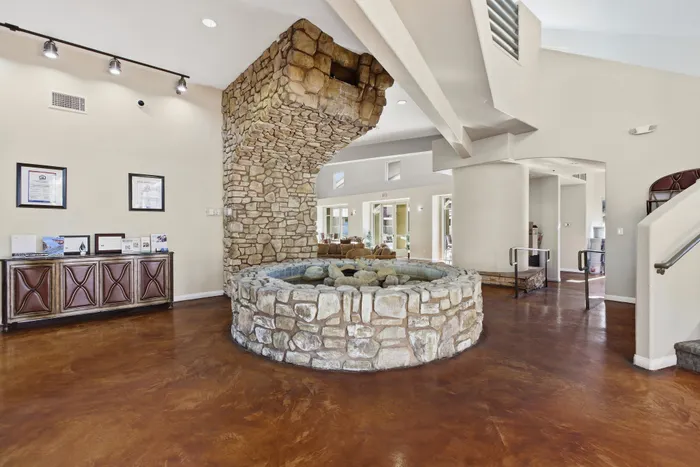 Luxurious apartment lobby featuring rustic stone architecture and elegant wooden flooring, creating a welcoming ambiance.