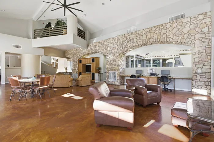 Spacious and elegant open living area featuring high ceilings, stone accent walls, and stylish furniture, perfect for modern living.