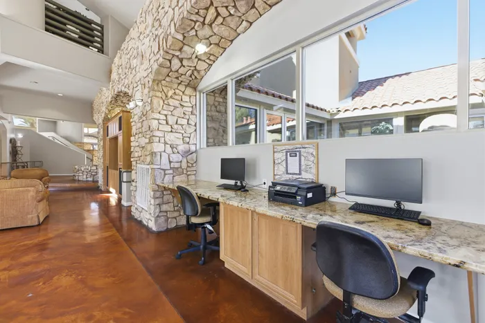 Chic communal workspace in a modern apartment complex with stone accent walls, sleek countertops, and large windows inviting natural light.