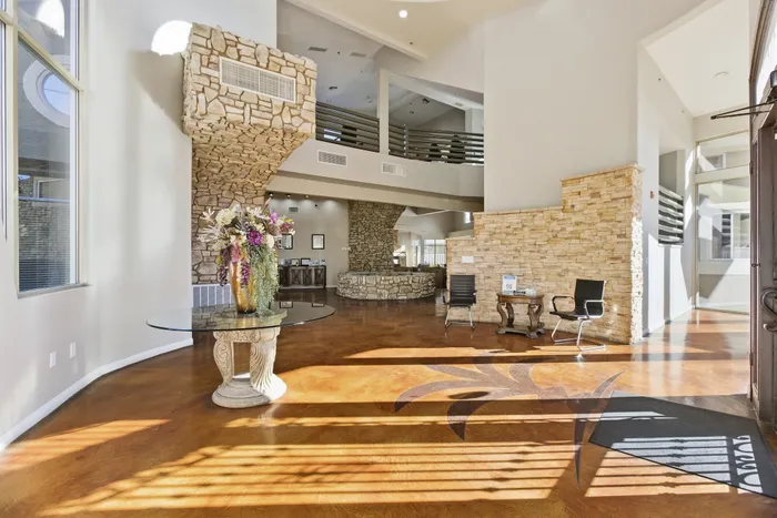 Inviting and elegant lobby with rustic stone accents, featuring a stylish glass table with floral arrangement, and warm natural lighting.