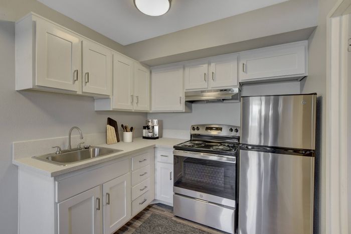 Modern kitchen with sleek stainless steel appliances, elegant white cabinetry, and a cozy layout perfect for culinary creations.