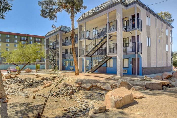 Modern multi-story apartment building with unique architectural design, surrounded by natural landscaping and ample outdoor space.