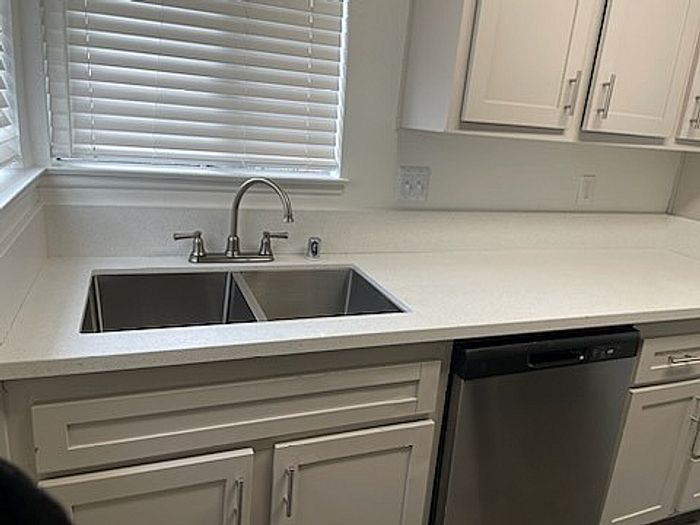 Modern kitchen featuring sleek stainless steel sink, bright cabinetry, and a convenient dishwasher under natural light.