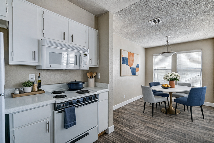 Charming kitchen with white cabinets, modern appliances, and cozy dining area featuring elegant seating and contemporary decor.