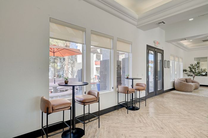 Modern lounge area with sleek high tables, plush seating, and abundant natural light, perfect for relaxation or social gatherings.