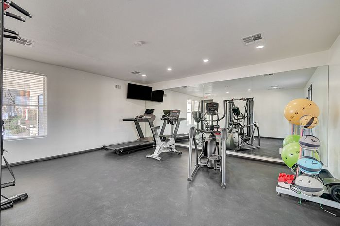 Modern apartment gym with state-of-the-art cardio machines, mirrored walls, and fitness equipment for a complete workout experience.
