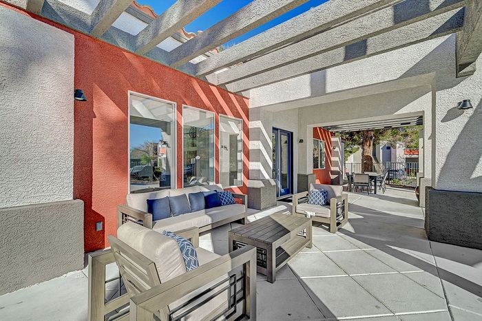 Sunlit modern patio with stylish outdoor seating under a pergola, perfect for relaxing and entertaining.