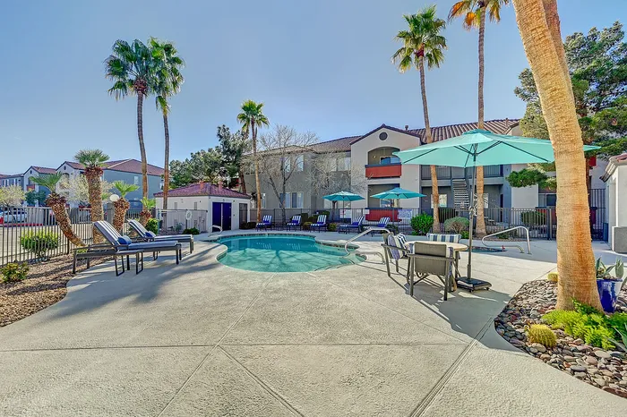 Charming outdoor space featuring a sparkling pool surrounded by comfortable loungers, vibrant palm trees, and stylish seating with umbrellas.