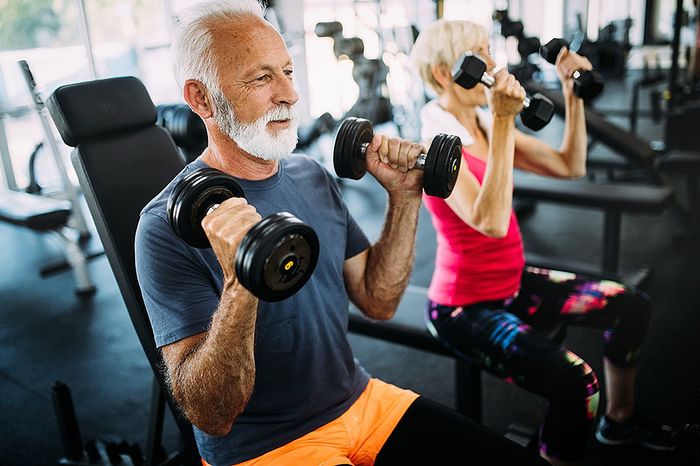 Energetic seniors enjoying a workout in a modern gym, lifting dumbbells and staying active.