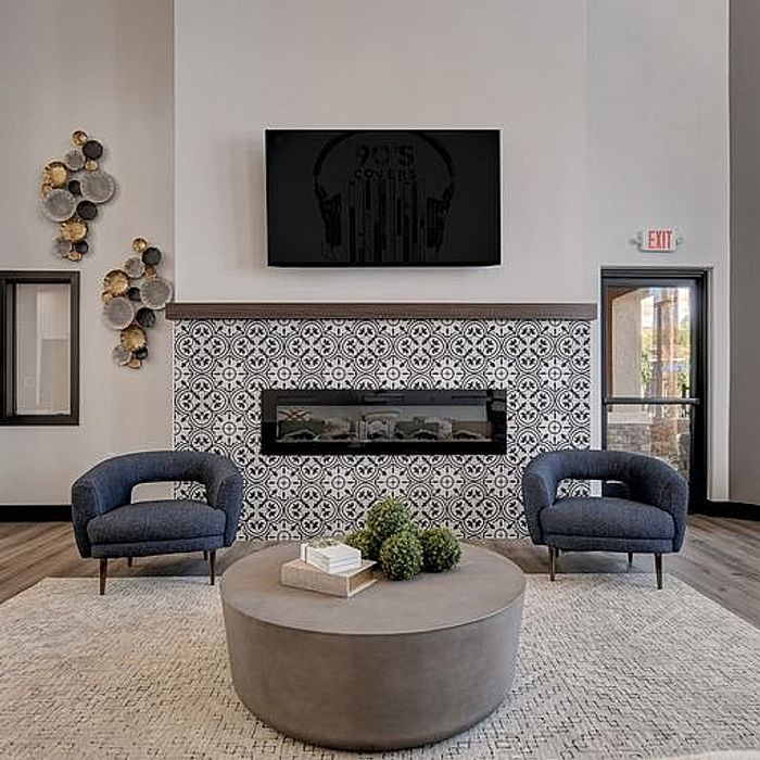 Elegant lobby with a modern fireplace, stylish blue chairs, and contemporary wall art creating a welcoming atmosphere.