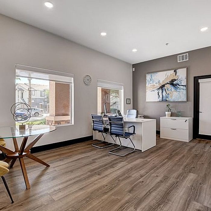 Modern and inviting office space with natural light, sleek wooden flooring, contemporary artwork, and stylish furniture.