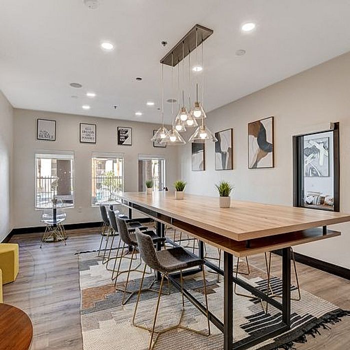 Modern dining room with ample natural light, featuring a long wooden table, stylish chairs, and contemporary art decor.