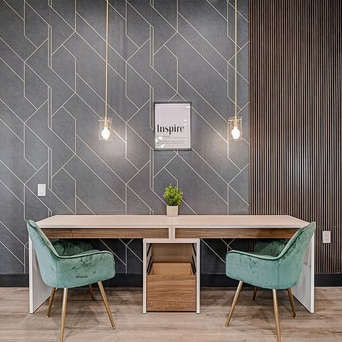 Modern workspace with chic design featuring a stylish desk, green velvet chairs, and elegant lighting.