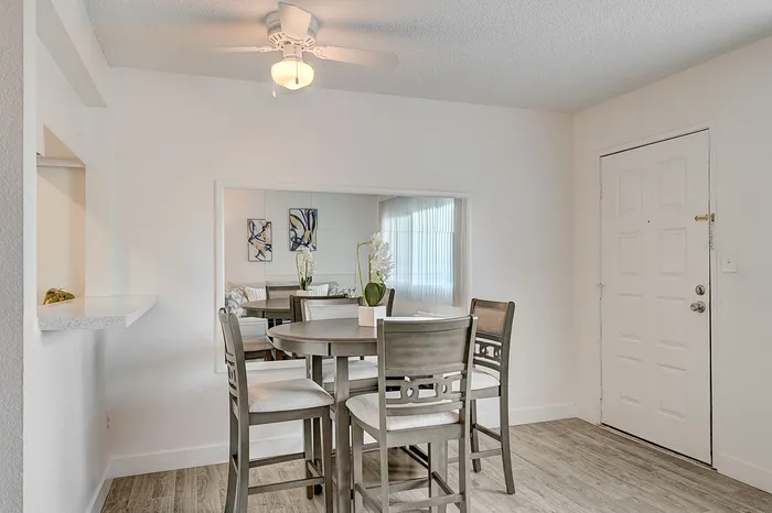 Charming dining area with sleek wooden furniture, mirrored wall, and bright natural light, ideal for cozy gatherings.