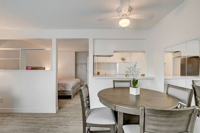 Inviting dining area with modern round table and chic chairs, adjacent to a cozy bedroom and a sleek, open-concept kitchen.