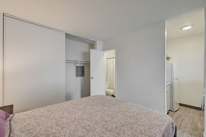 Inviting bedroom with plush bedding, spacious closet, and a connected bathroom, leading to a bright kitchen with modern amenities.