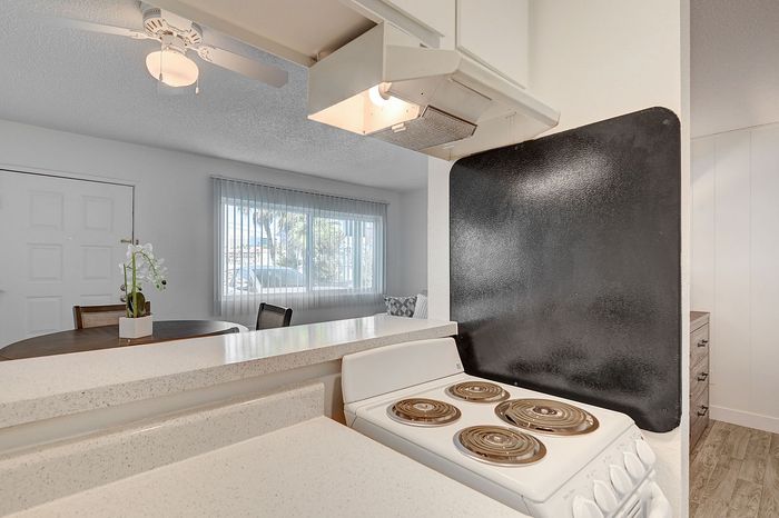 Bright and airy kitchen with modern electric stove, adjacent to a cozy dining area, enhanced by natural light from large windows and elegant design.