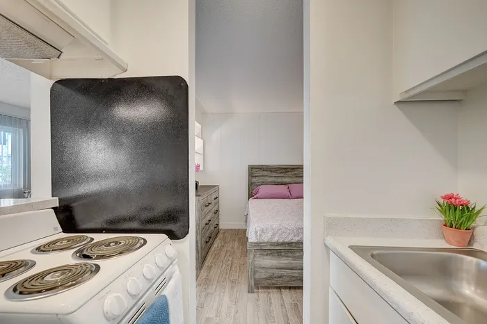Inviting apartment interior featuring a cozy bedroom with soft lighting, a modern kitchen area with a sleek stove, and a touch of greenery for a warm ambiance.