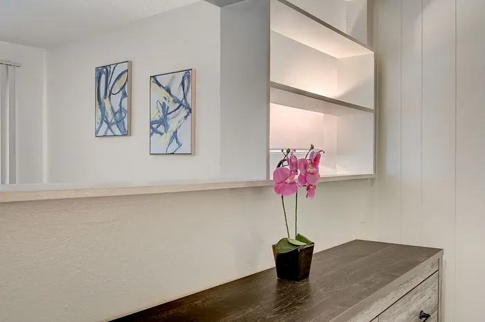 Chic interior with open shelving, artistic wall decor, and a vibrant orchid enhancing the modern ambiance.