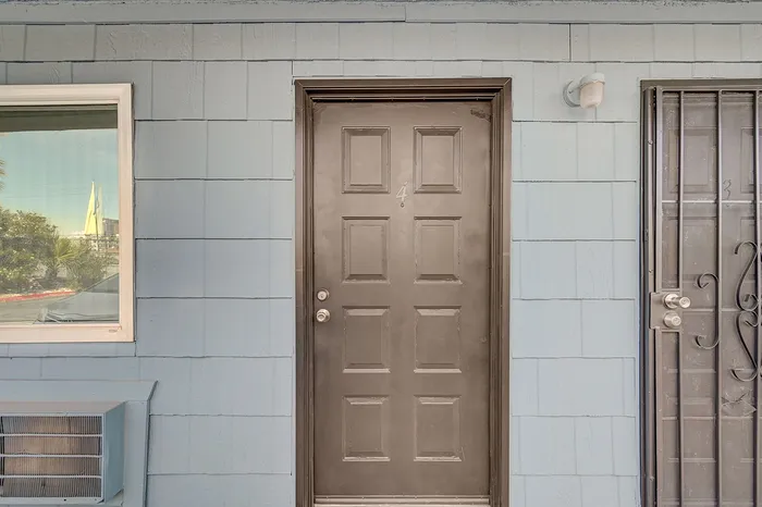 Inviting apartment entrance with a stylish dark wood door on a charming light blue exterior, featuring modern design elements.
