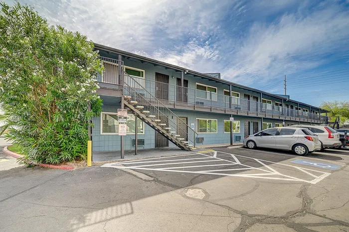 Charming two-story apartment building with modern balconies, ample parking, and lush greenery, perfect for convenient urban living.