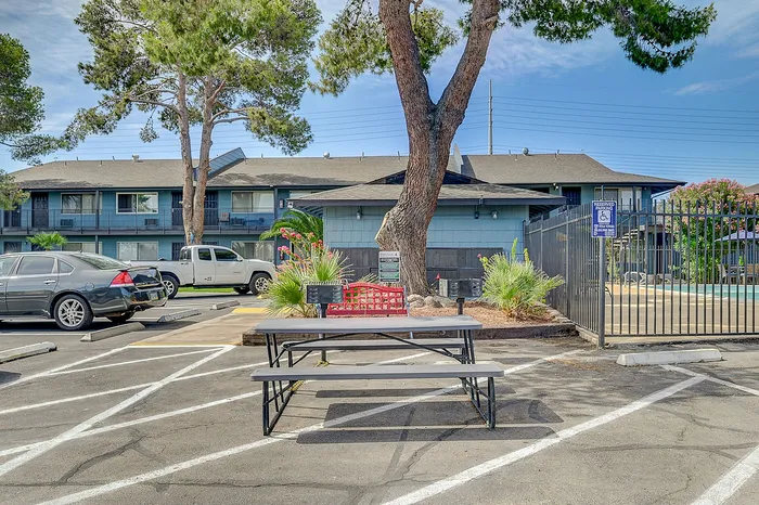 Charming apartment complex featuring a picnic area with benches and vibrant landscaping, offering a serene and inviting outdoor space.