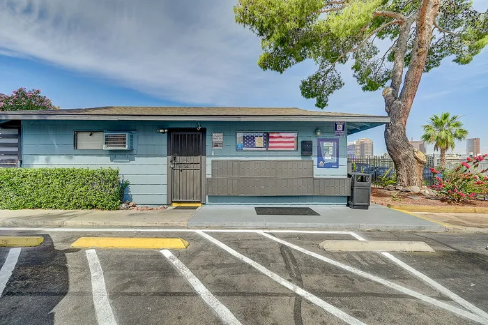 Charming blue office building with vibrant American flag display, surrounded by lush greenery and cityscape views.