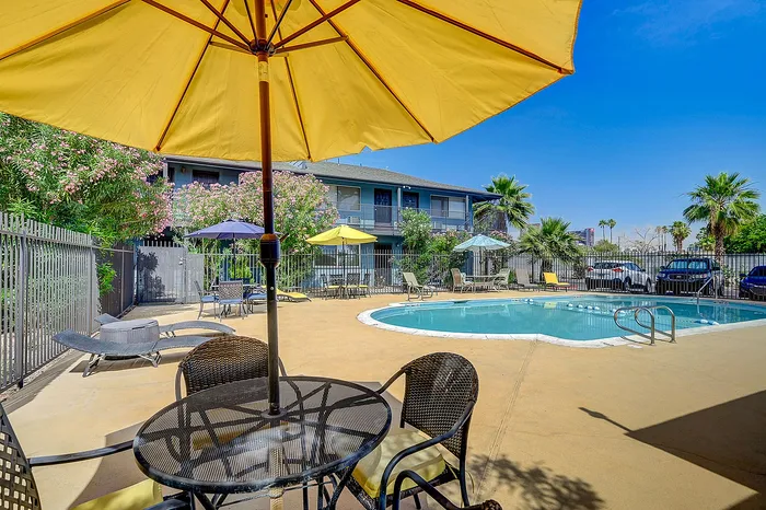 Inviting outdoor pool area with bright yellow umbrellas, surrounded by lush greenery and comfortable lounge seating.