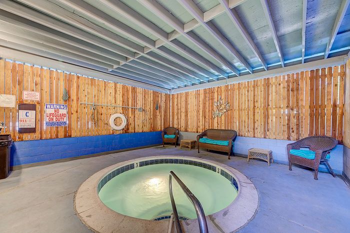 Inviting indoor spa area featuring a cozy hot tub surrounded by stylish wicker seating, set against rustic wooden paneling for a relaxing retreat.