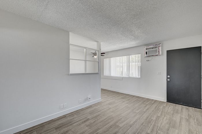 Bright and airy living space with modern laminate flooring, large window for natural light, and sleek open shelving.