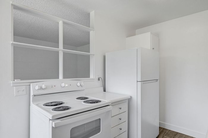 Modern kitchen featuring a sleek white stove, spacious countertops, and minimalistic design, ideal for culinary creativity.