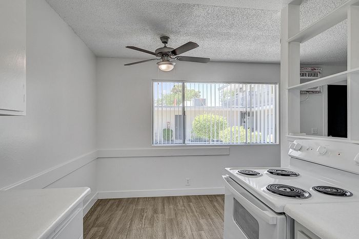 Bright, modern kitchen with a ceiling fan, electric stovetop, and large window offering natural light and a charming view.