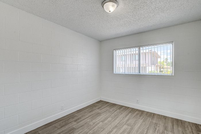 Bright and inviting room with modern wood flooring and a large window offering natural light.