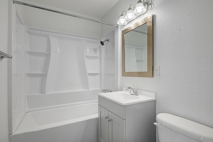 Elegant modern bathroom with a sleek white bathtub and a stylish vanity mirror, perfect for relaxation.