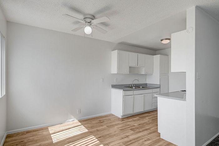 Bright, minimalist kitchen with white cabinetry, modern fixtures, and warm hardwood flooring, perfect for culinary creativity.
