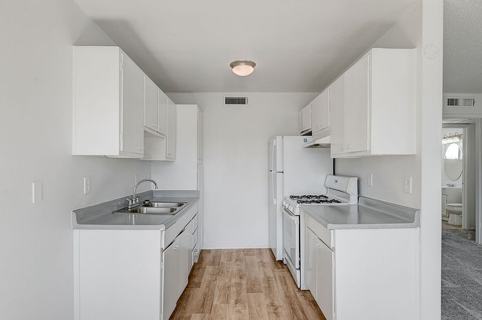 Bright and modern kitchen with sleek white cabinetry, dual sinks, and a cozy open layout, exuding a warm inviting ambiance.