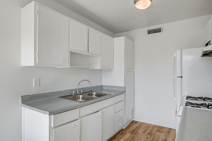 Elegant kitchen featuring pristine white cabinetry, sleek countertops, and a double sink with modern fixtures.