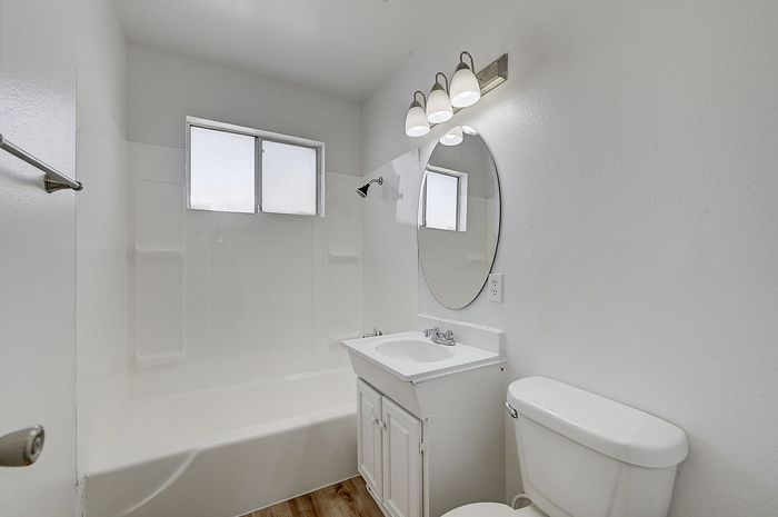 Bright and airy bathroom featuring modern fixtures, a sleek white vanity, and a large mirror enhancing the space.