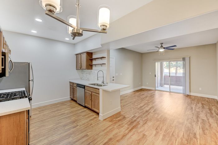 Bright, open-concept kitchen and living area with wooden floors, modern fixtures, and large sliding doors leading to a patio.